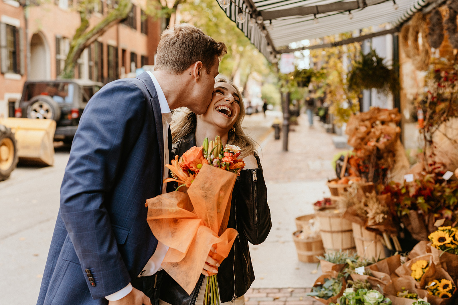 the man cheeks the cheek of his future bride while she laughs and holding a bouquet