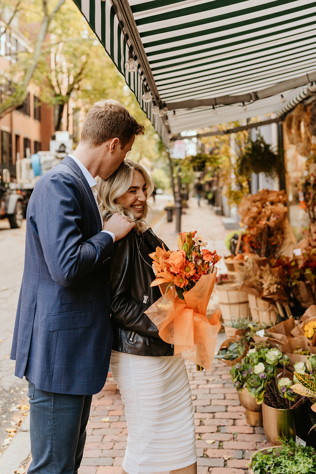 engaged couple in front of a boston florist, holding a bouquet