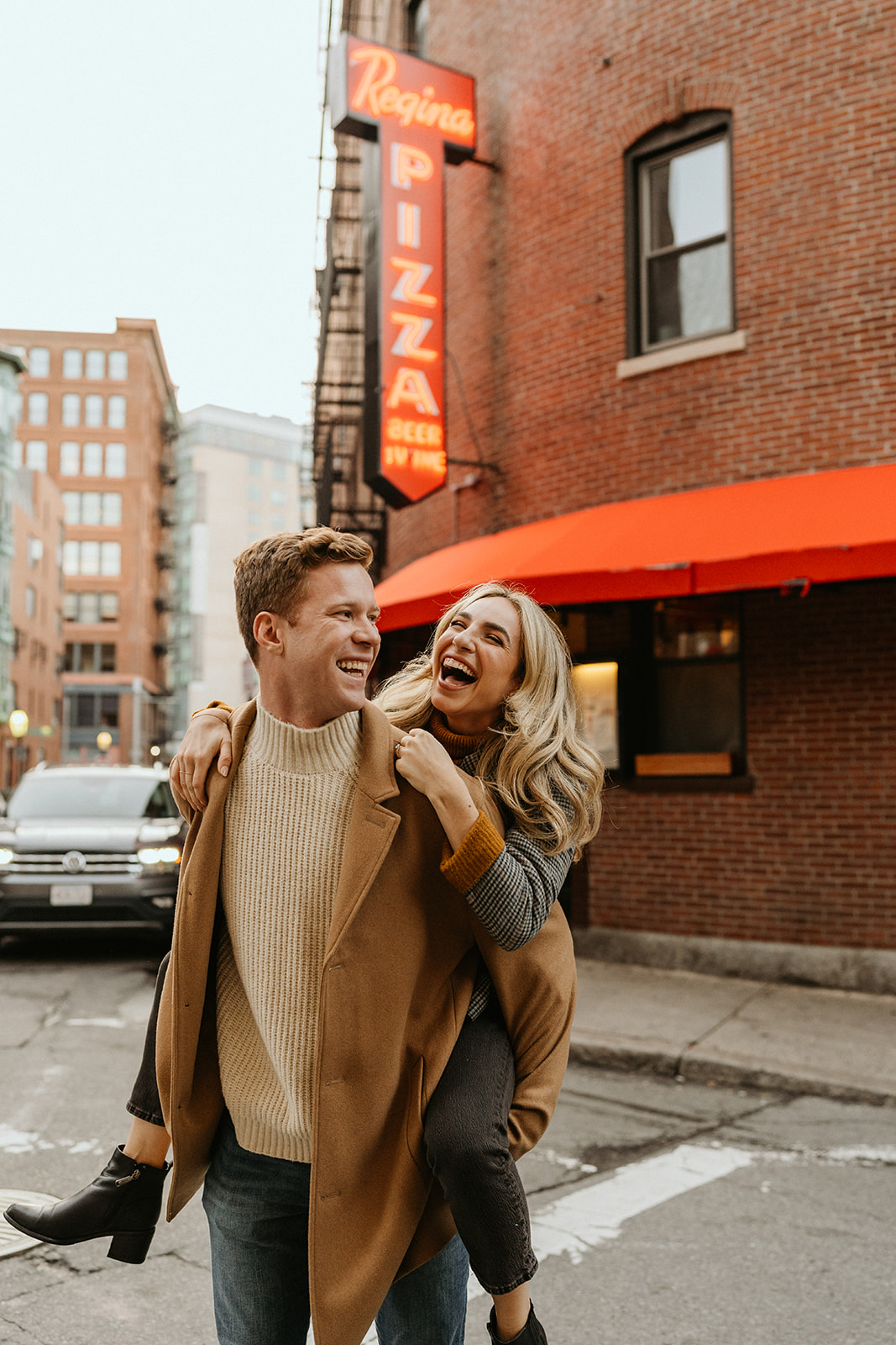 engaged couple piggy backing, candid poses and laughing in Boston streets