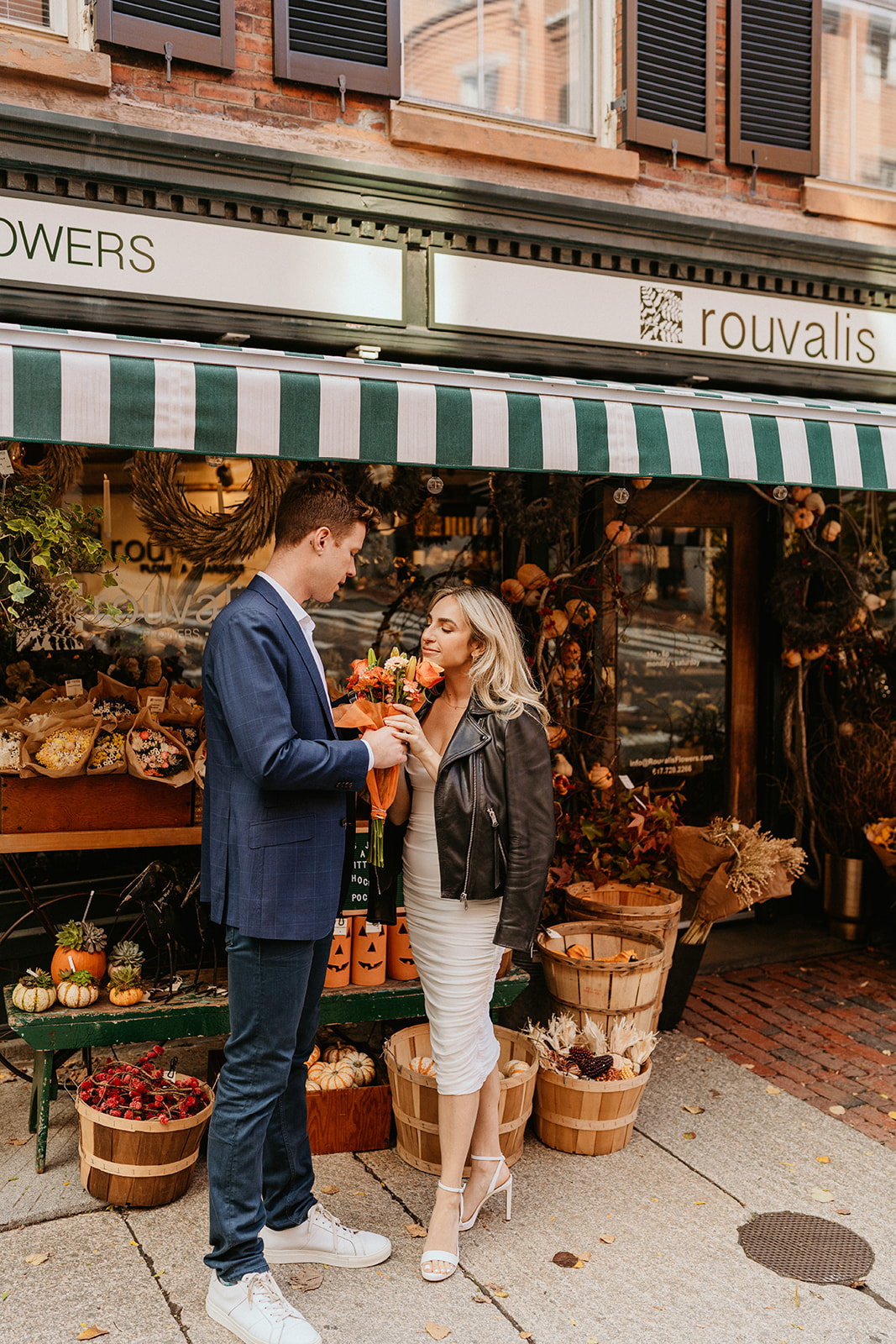 a woman smells her fall bouquet in front of a florist shop in Boston