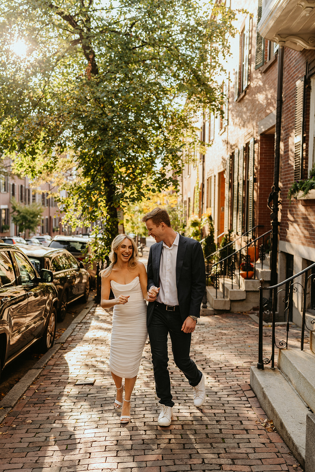 engaged couple walking holding hands laughing in Boston