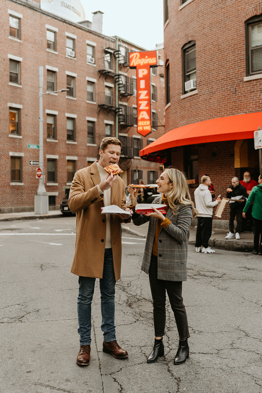 engaged couple eating pizza int he streets of boston