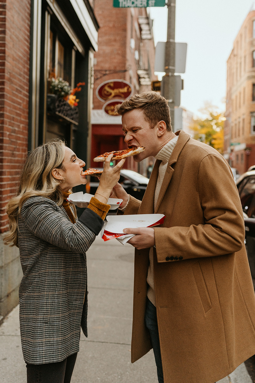 engaged couple feeding each other pizza for their fun engagement photoshoot