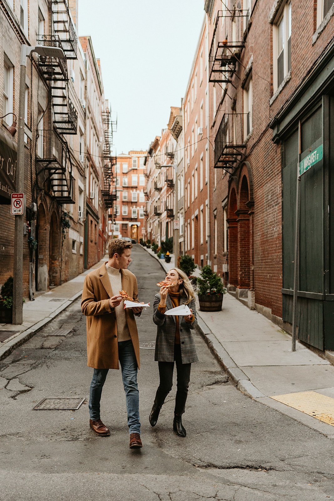 couple walkign while eating Pizza in Boston