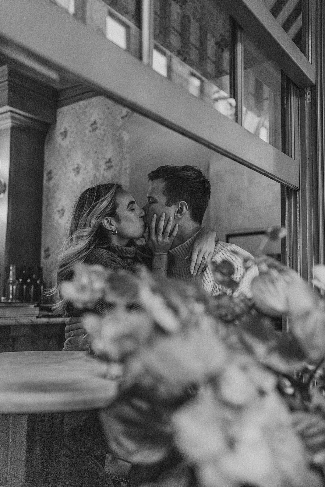 engaged couple kissing in a cafe for romantic engagement photoshoot