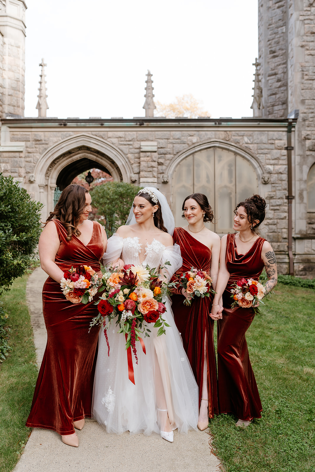 bride and bridesmaids wearing red velvet bridesmaids dresses for a fall wedding