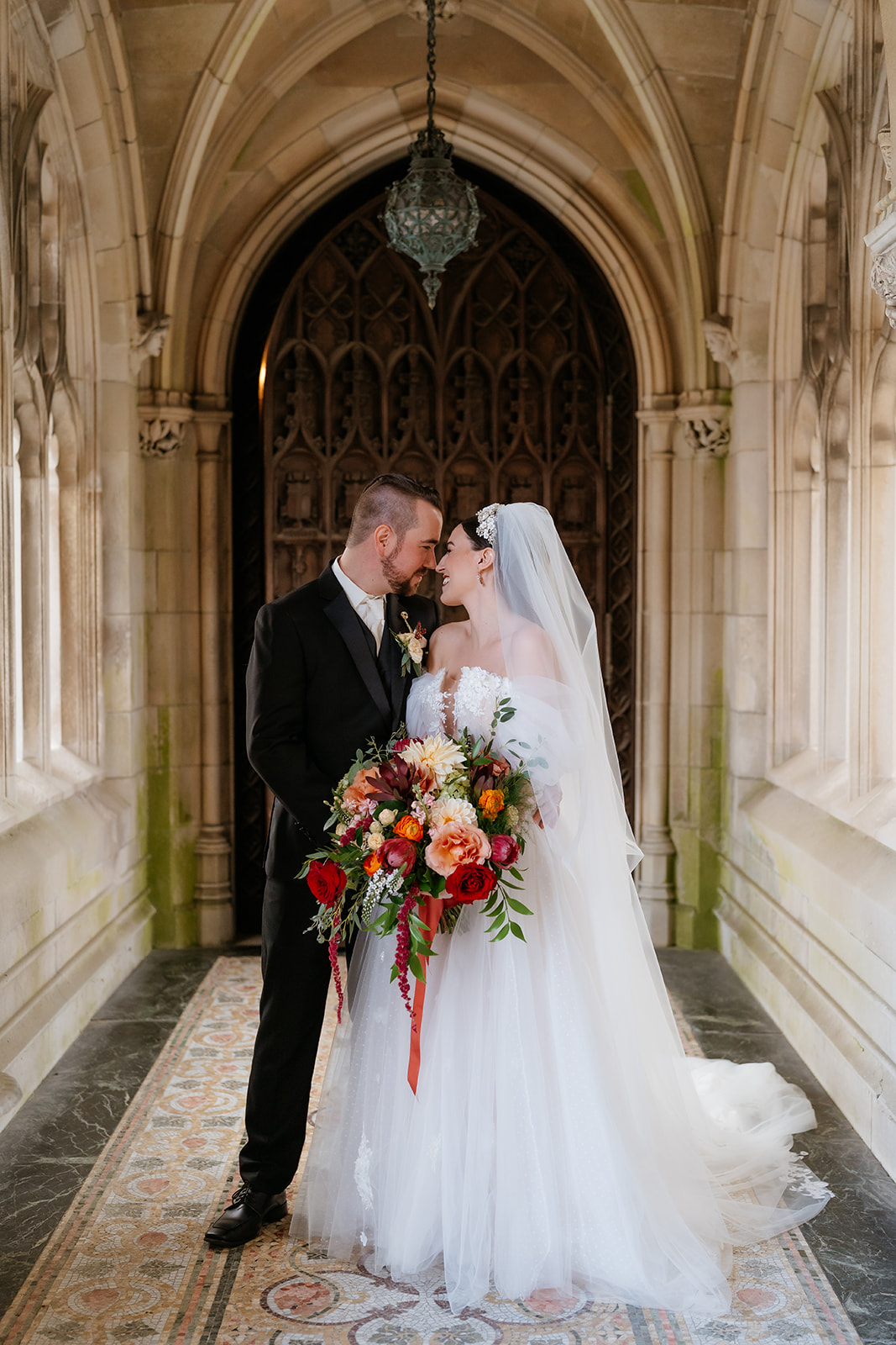 wedding portrait of bride and groom as she holds a fall wedding bouquet