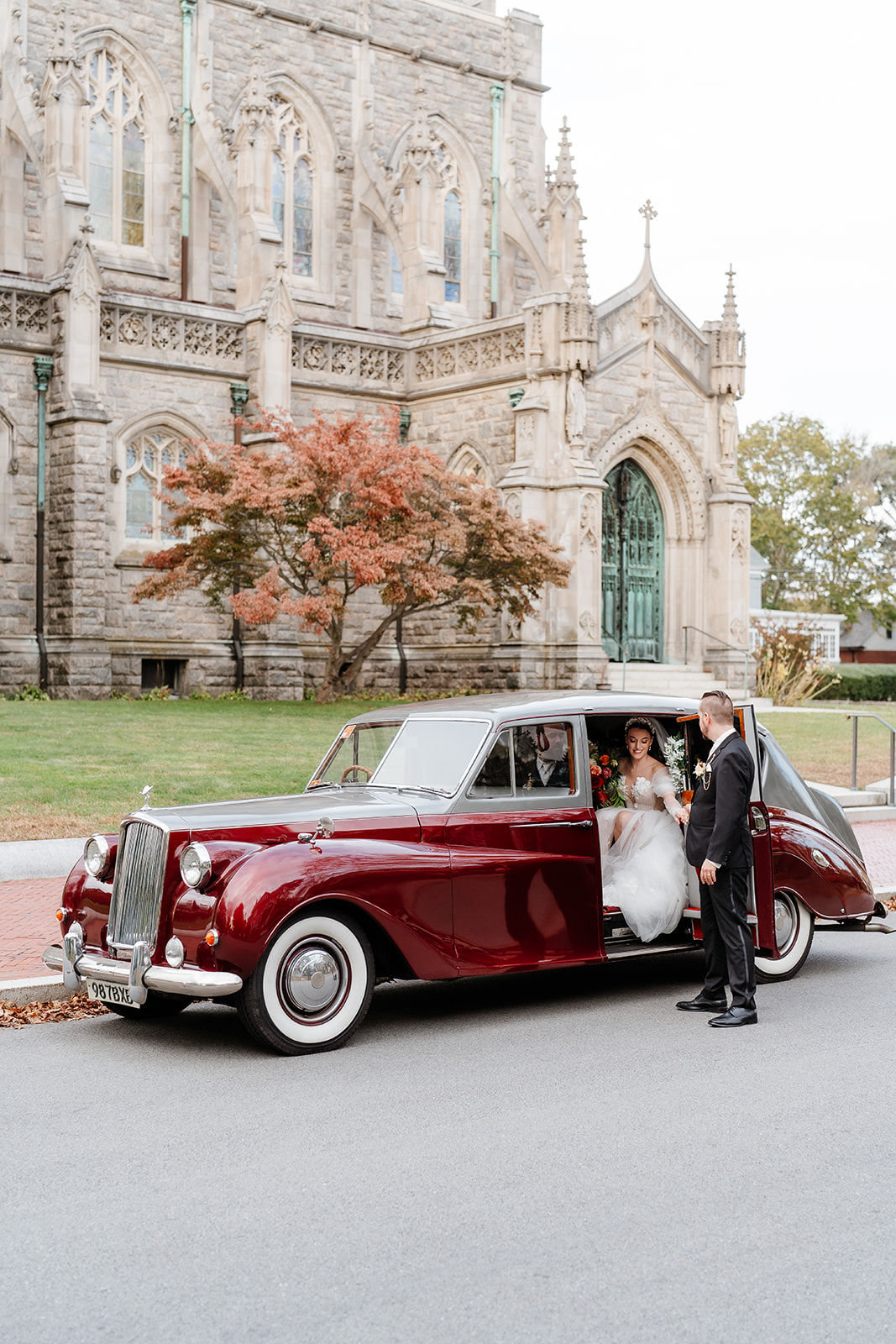 groom helping his bride out of the vintage car for their wedding ceremony in the church
