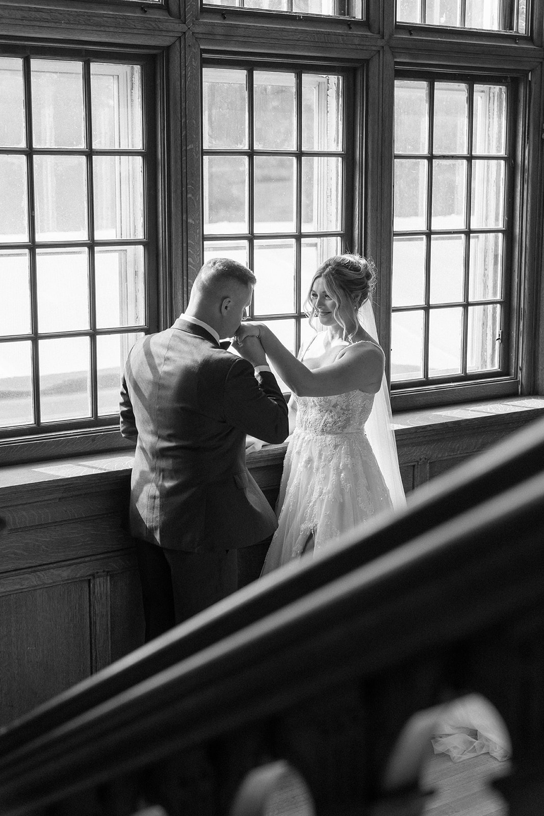 groom kisses bride's hand in a black and white photo