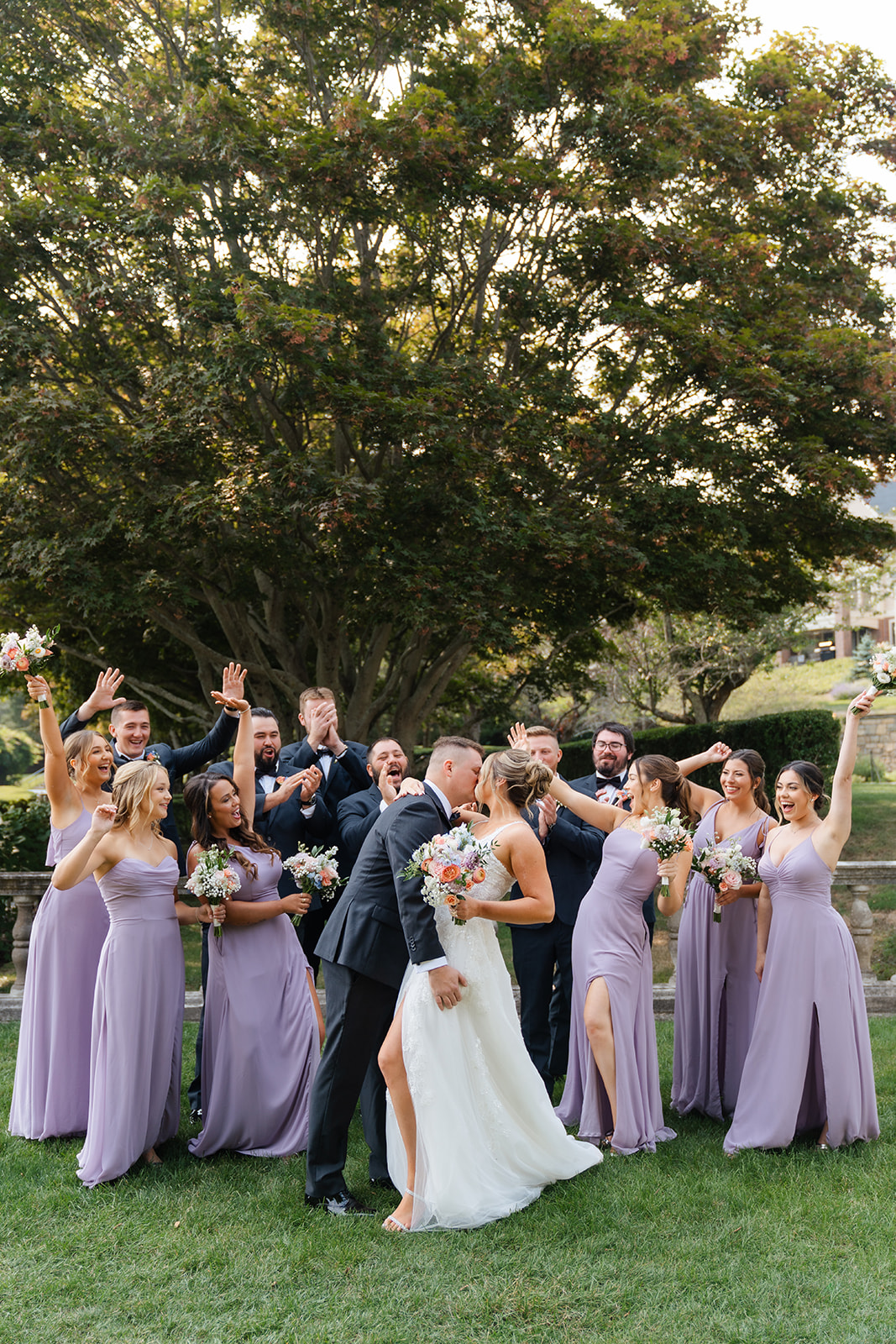 fun bridal party photo while the couple kisses