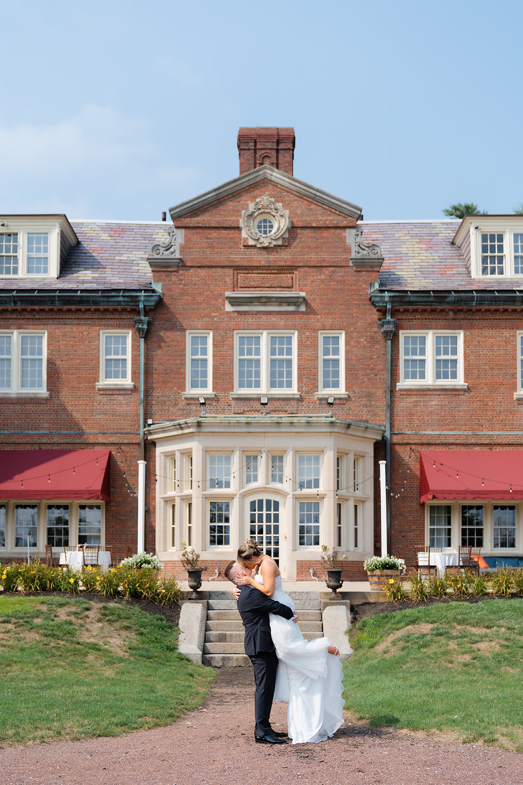 a romantic photo of groom picking up the bride in front of the Mansion on Turner Hill 