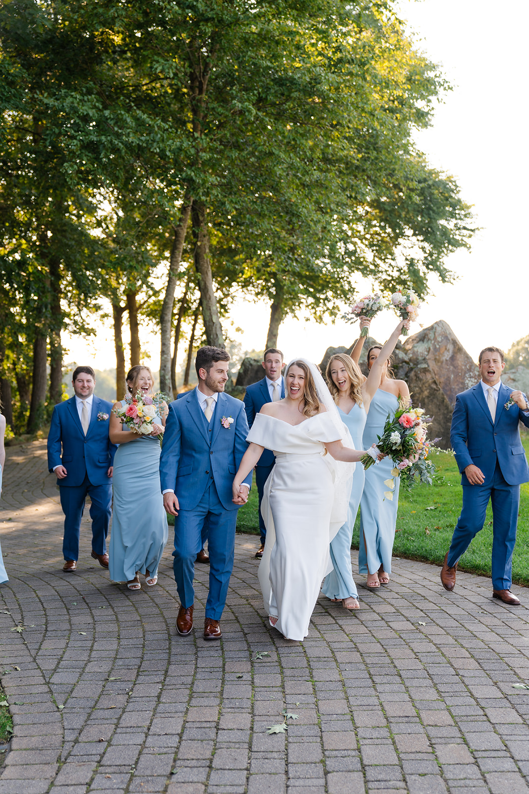 candid bridal party photo, bride and groom holding hands walking