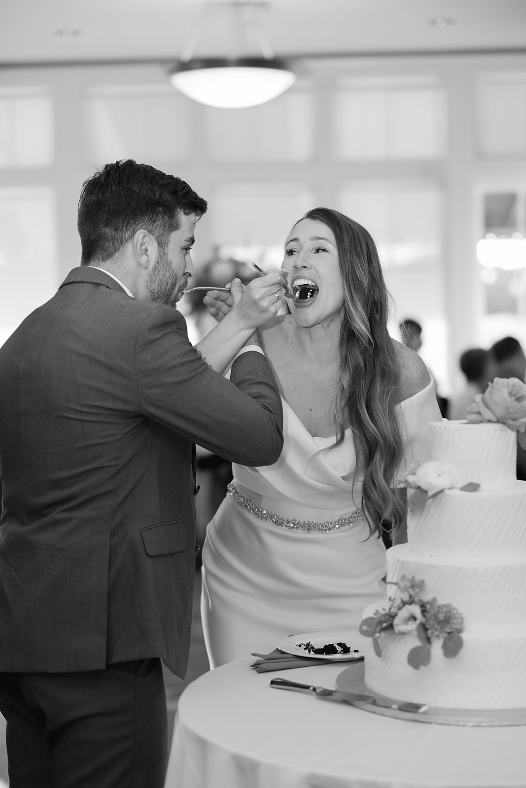 bride and groom feeding each other the first bite of the wedding cake