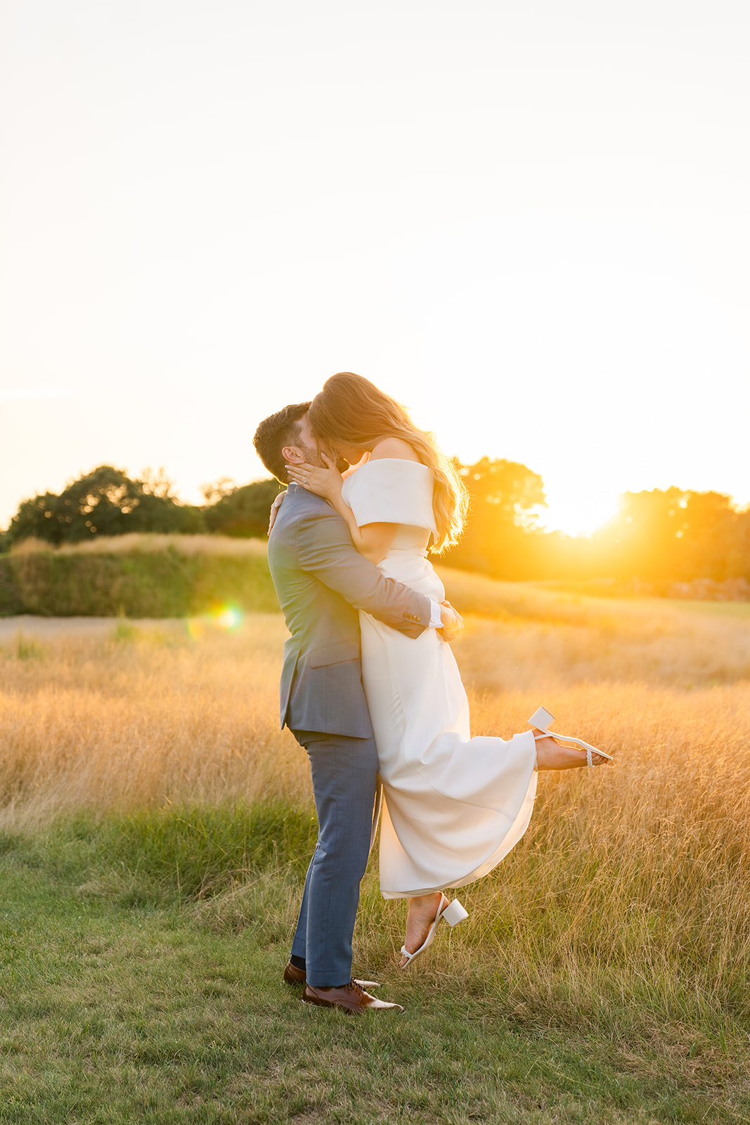 sunset wedding photo of bride and groom kissing 