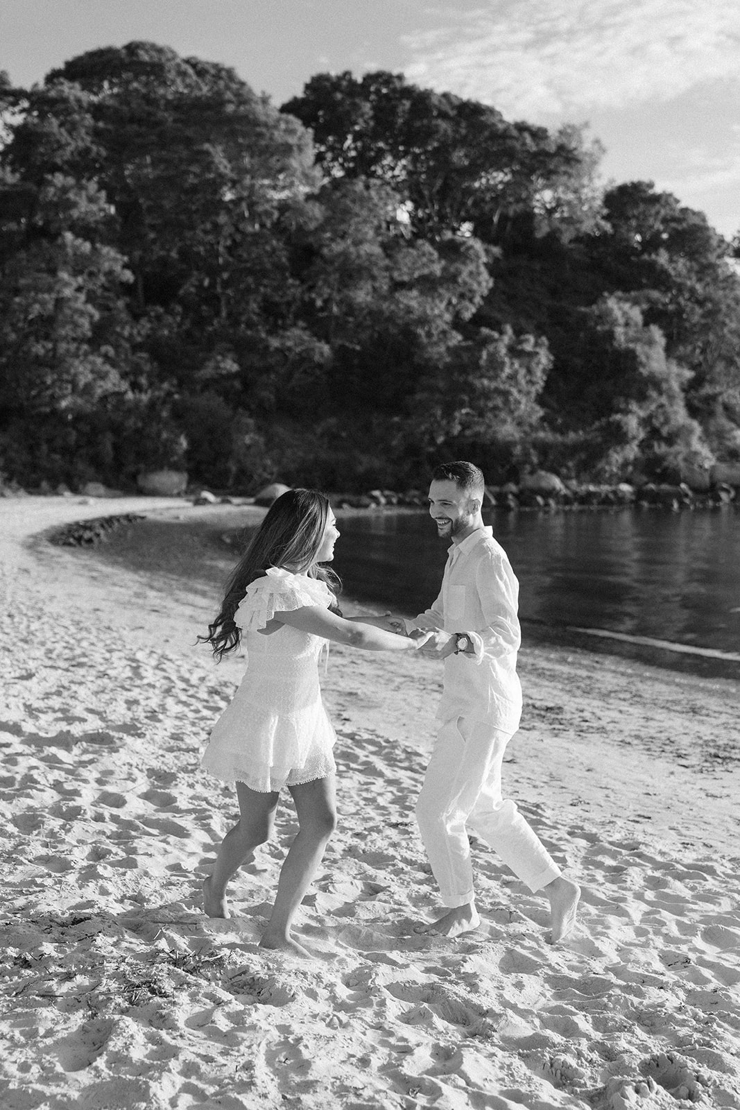 A couple twirling and laughing on the sand at Old Silver Beach, captured in a joyful moment as they enjoy their Cape Cod Engagement Photos during sunset.