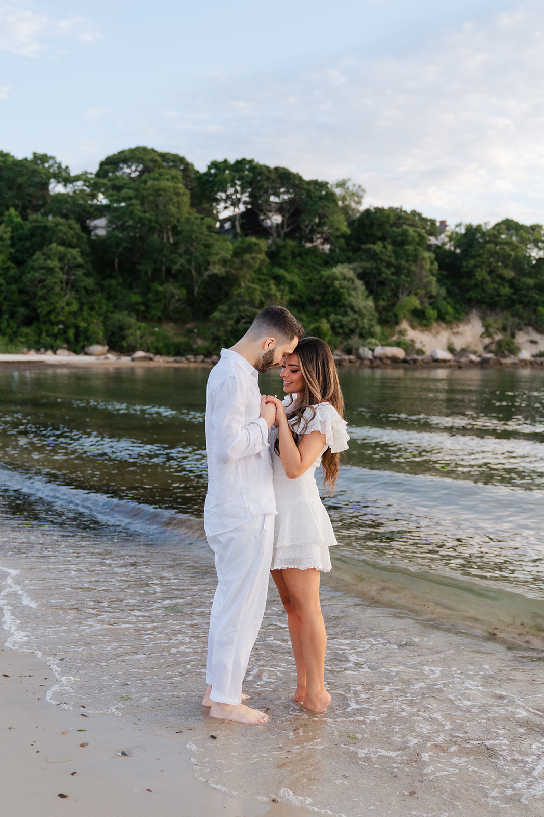 Cape Cod Engagement Photos of a couple in love, holding each other close on the beach as the sky fills with a warm, golden glow.