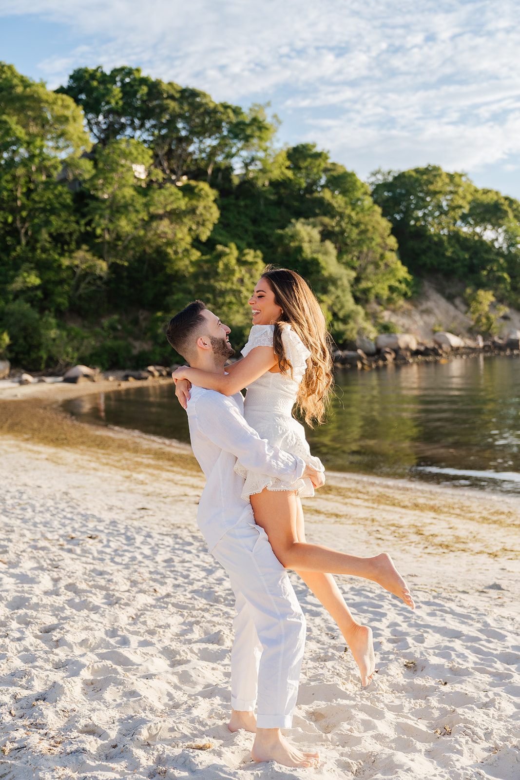 A couple sharing a lift on the beach, with the golden sun in the background, capturing the warmth and romance of a Cape Cod engagement session.