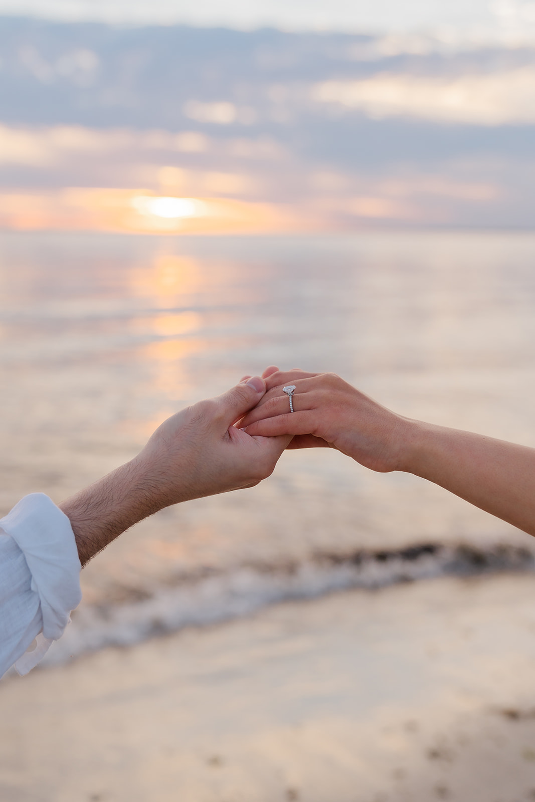 Couple holding hands as the sun sets in the background