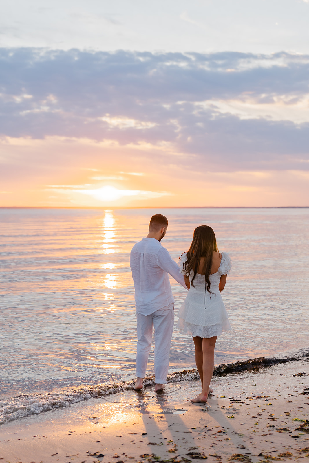 Couple holding hands as they watch the sunset on the beach