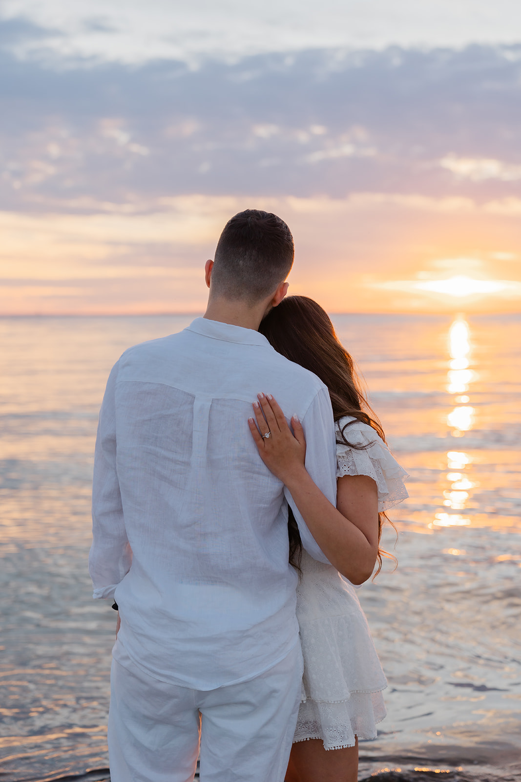 Couple holding eachother as they watch the sunset on the beach