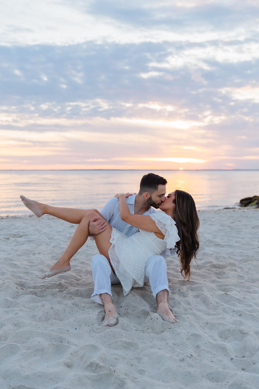 Cape Cod Engagement Photos of a couple sitting on the sand kissing