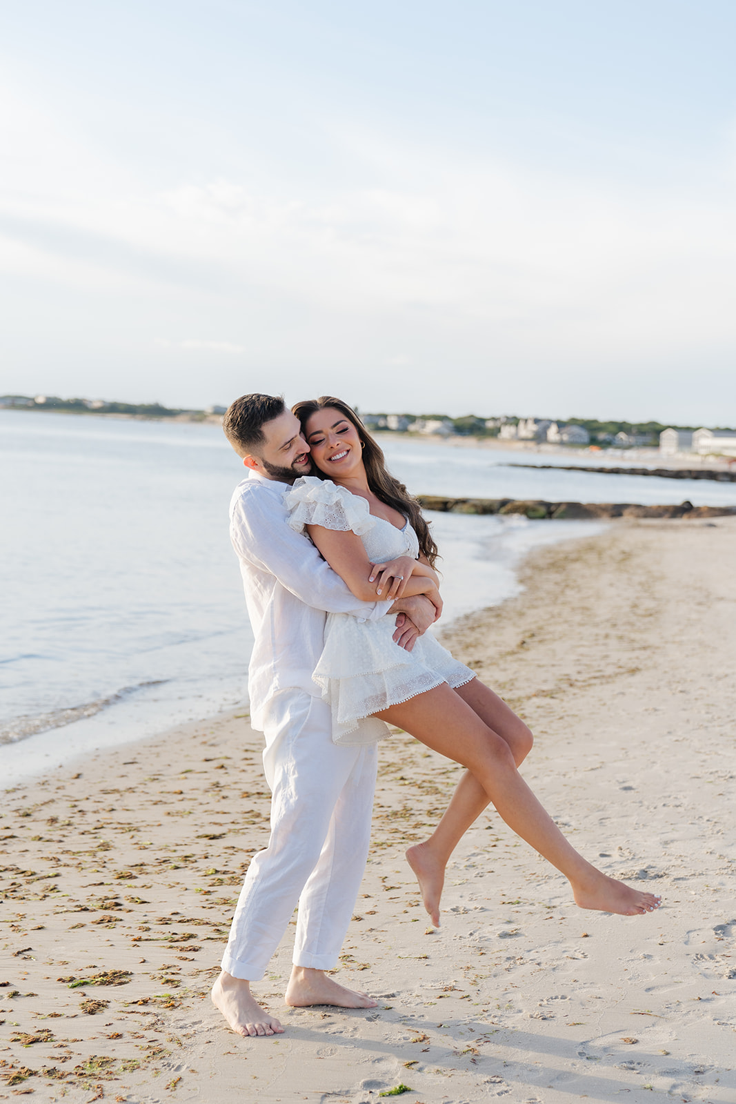 A couple sharing a lift on the beach, with the golden sun in the background, capturing the warmth and romance of a Cape Cod engagement session.