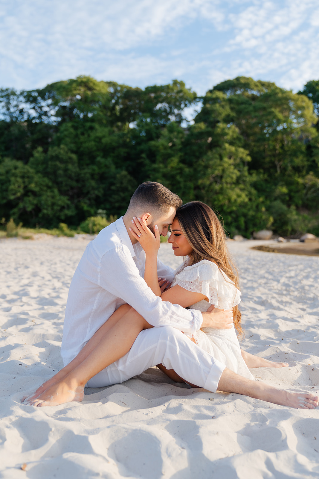 A tender moment captured as the couple sits on the sand at Old Silver Beach, enjoying each other’s presence in a romantic, relaxed pose during their Cape Cod engagement photoshoot.