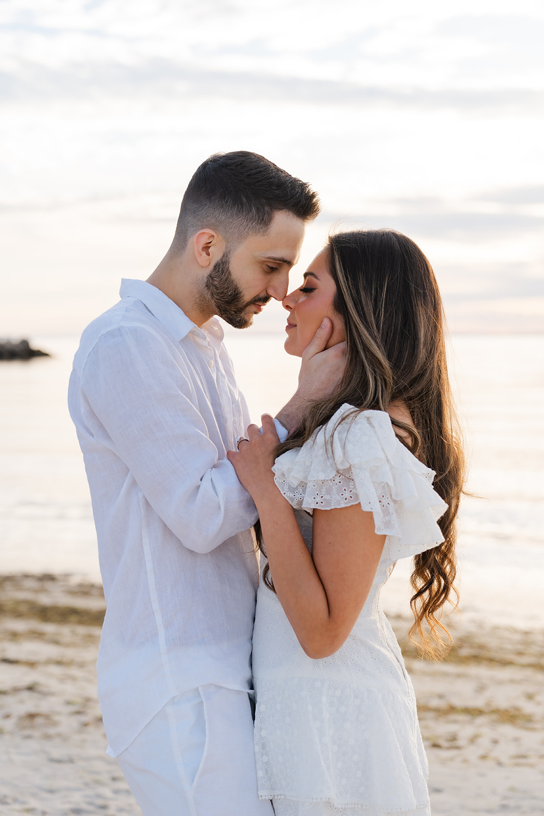 A romantic moment between the couple as they gently touch foreheads, embracing each other on Old Silver Beach, captured beautifully in this Cape Cod engagement photo.