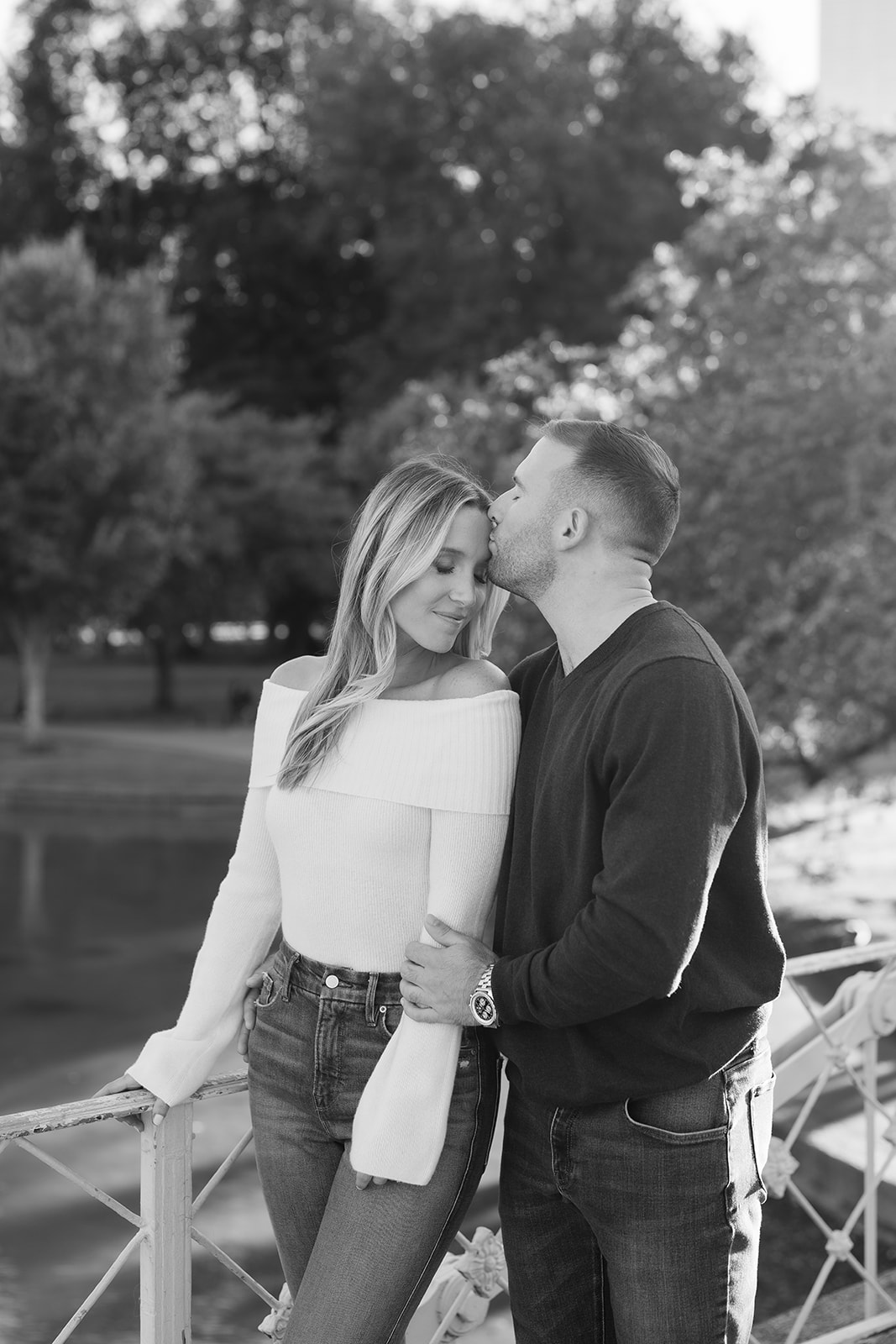 Romantic black and white photo of a couple sharing a sweet kiss by the bridge in the Boston Public Garden, capturing a timeless moment for engagement photos