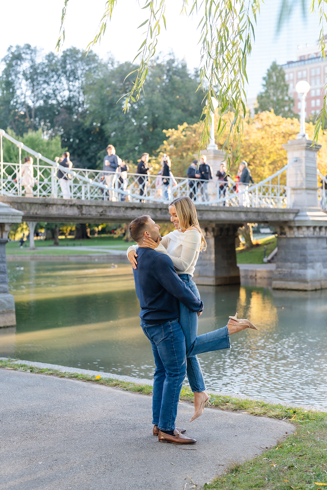 Couple sharing a joyful moment by the water in the Boston Public Garden during their engagement photoshoot