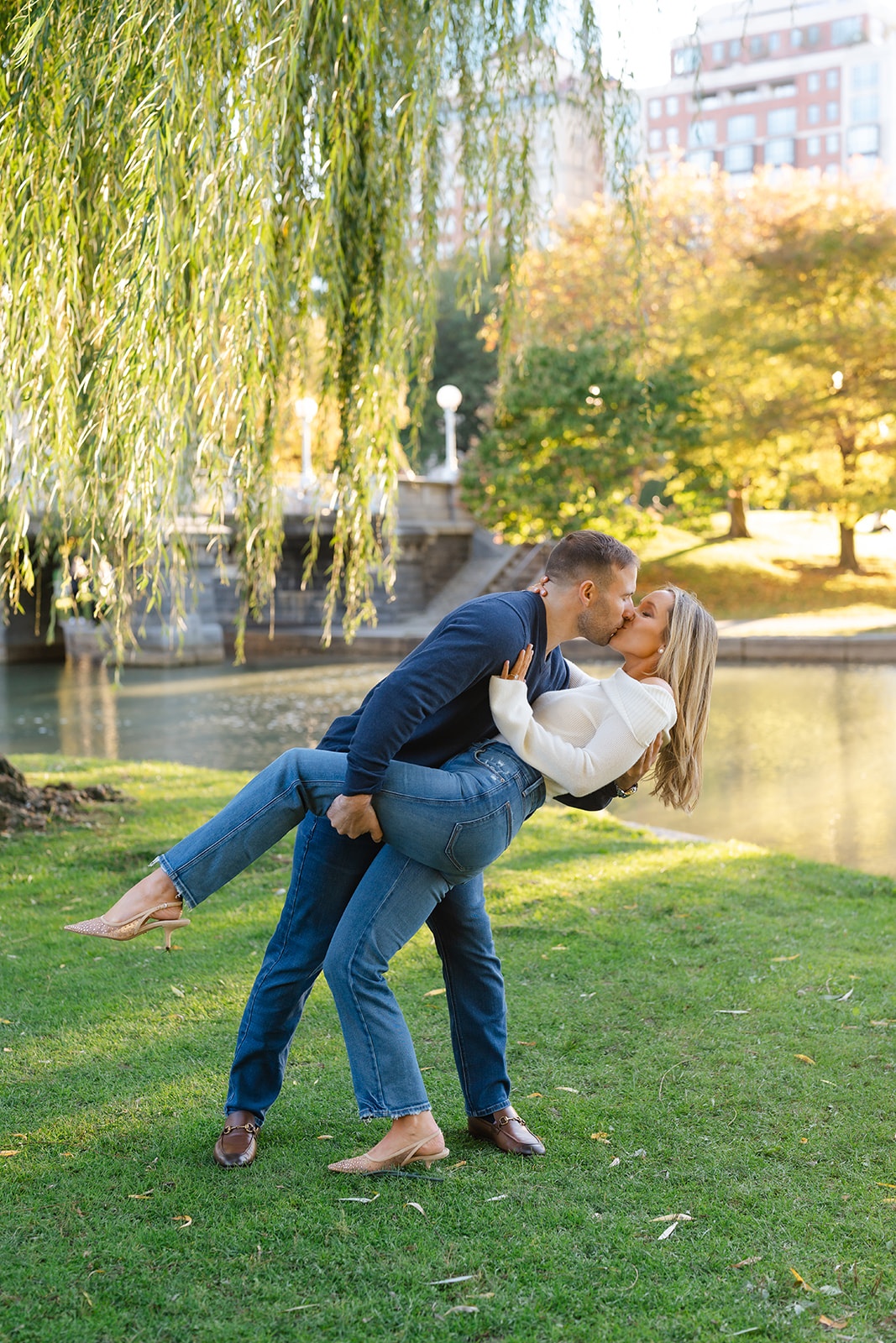 Couple sharing a joyful moment by the water in the Boston Public Garden during their engagement photoshoot.