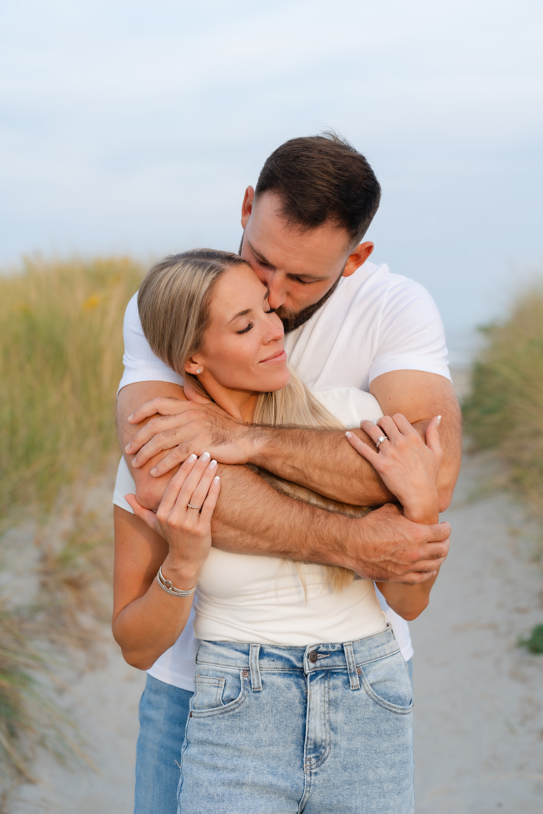 Candid moment of a couple enjoying a relaxed moment together during their beach engagement session, captured on a calm, beautiful beach path.