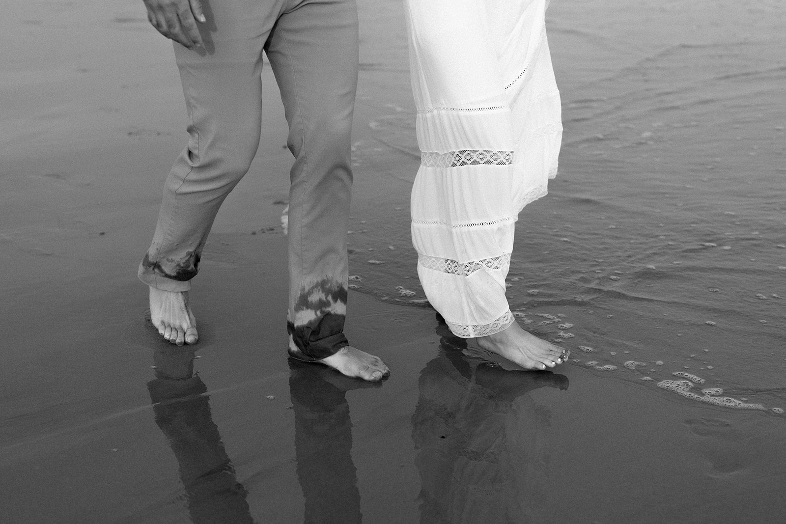 Black and white photo of couple walking on the beach