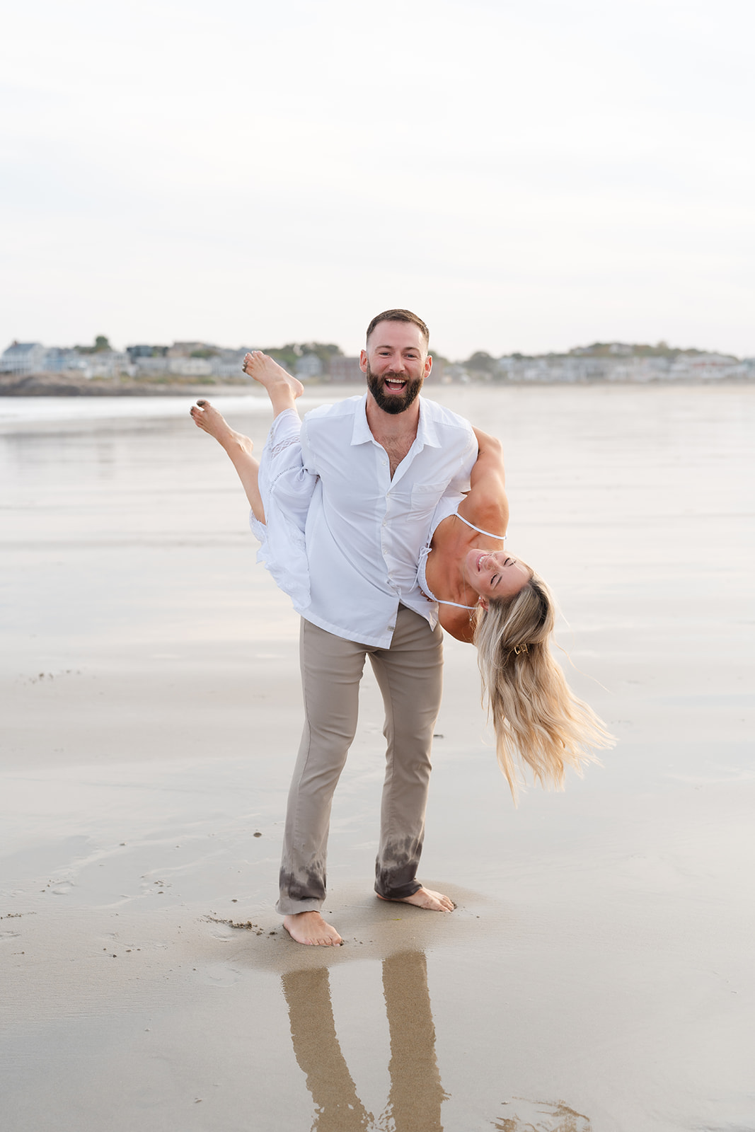 partner lifting the other, creating a romantic and fun moment during their Beach Engagement session.