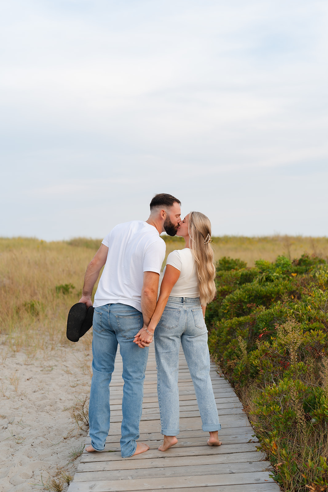 Couple walking hand-in-hand on a beach path during their beach engagement session, with a relaxed and romantic vibe.