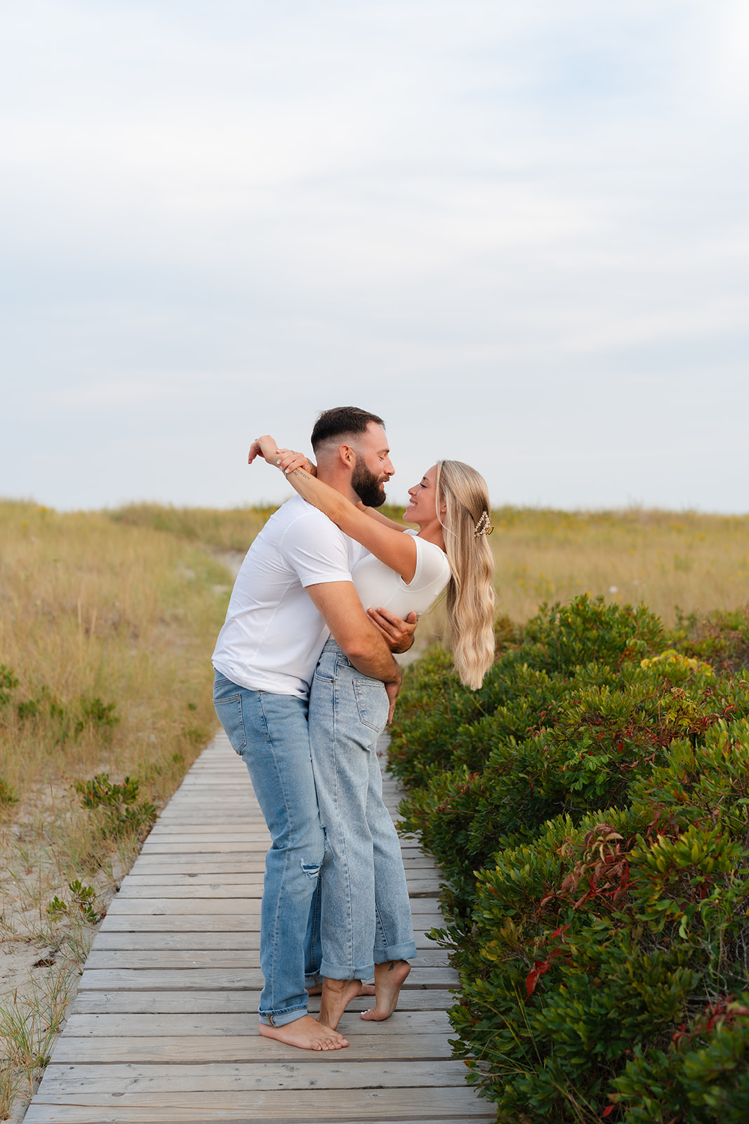 Fun and playful beach engagement photo with the couple embracing and twirling on a sandy beach walk.