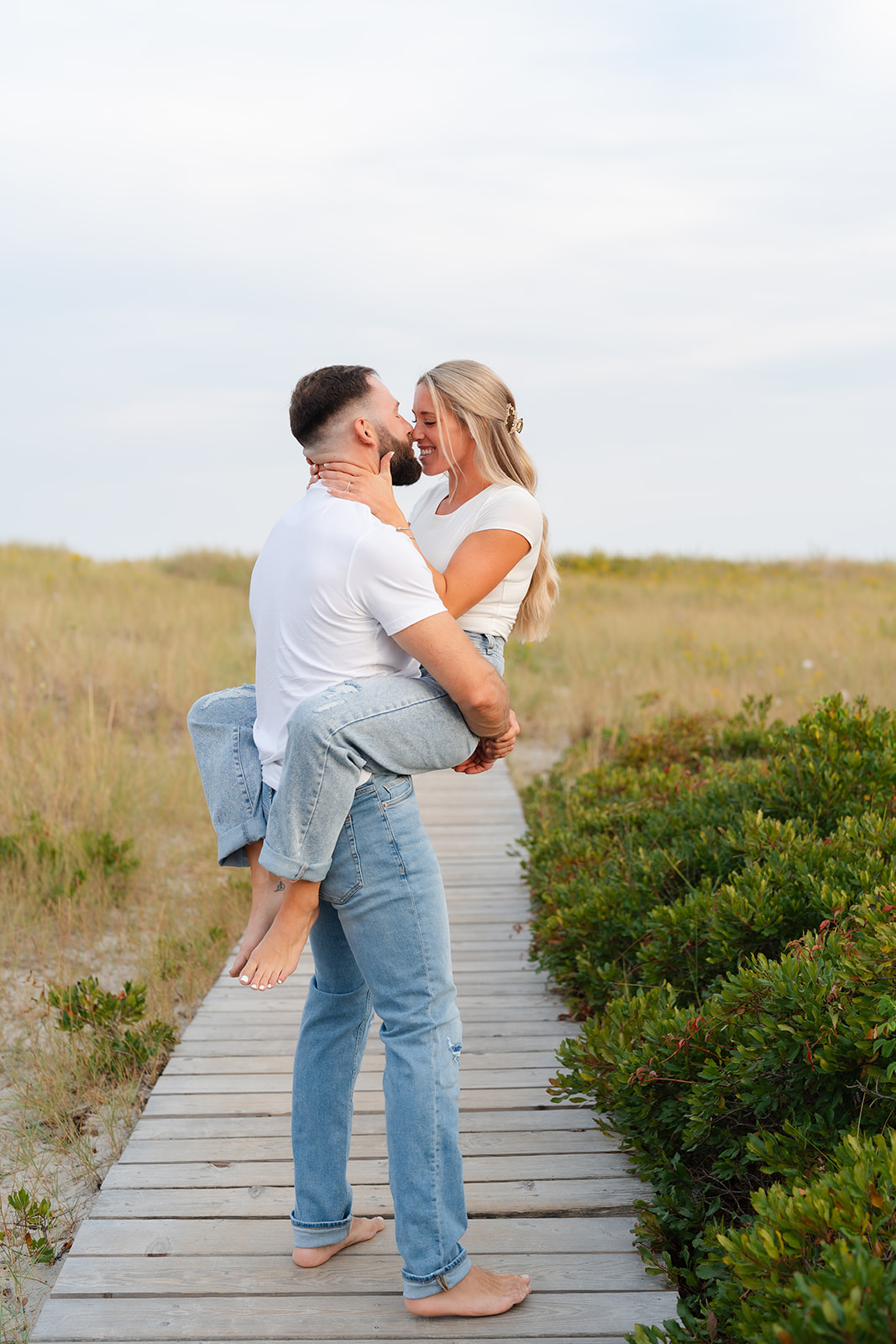 Candid beach engagement photo of the couple sharing a loving moment, surrounded by nature, perfect for capturing genuine emotions.