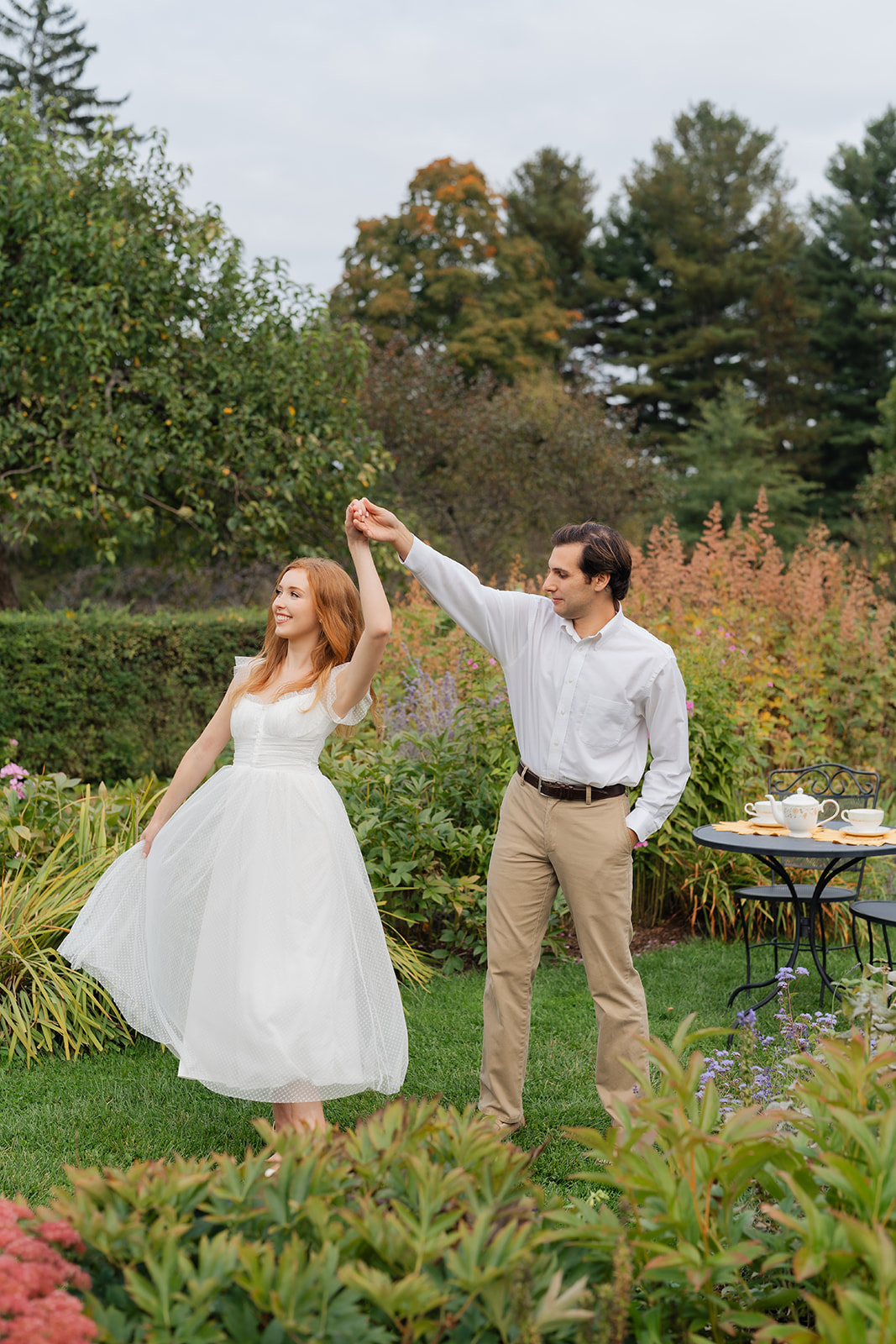 A woman spinning in her dress while her fiance twirls her, creating fun and memorable moments at their engagement shoot with unique engagement shoot ideas at Stevens-Coolidge.