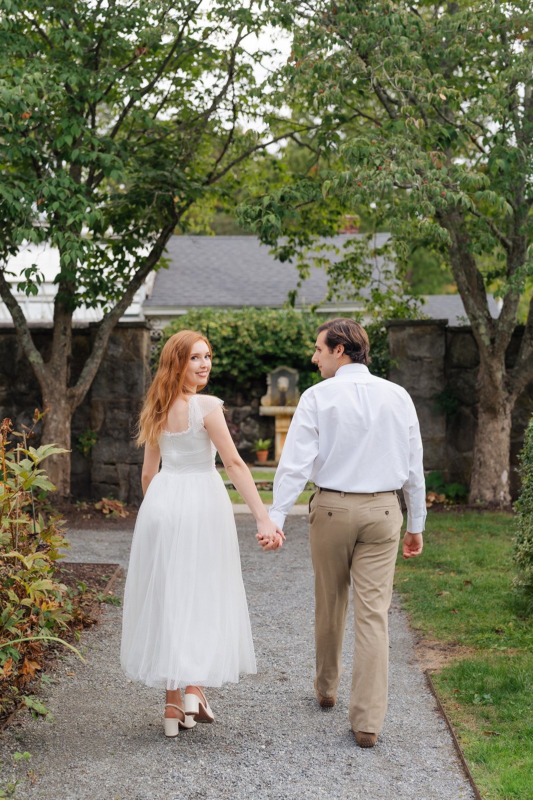 A couple sharing a quiet, tender moment by a beautifully intricate gate, showing their love through unique engagement shoot ideas in an elegant garden setting.