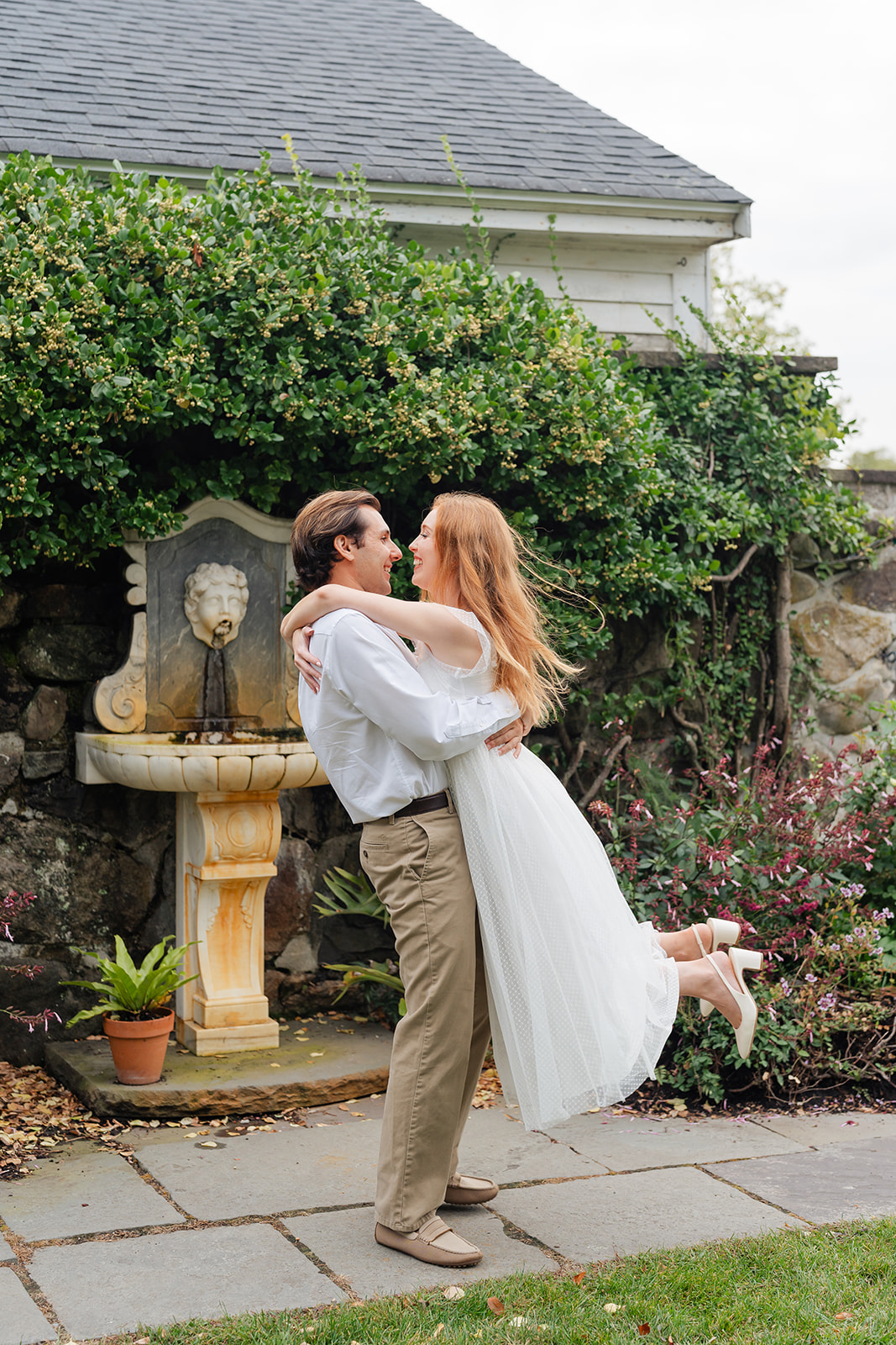 Couple spinning in a garden of colorful dahlias, creating an energetic and joyful moment captured with unique engagement shoot ideas at Stevens-Coolidge House & Gardens