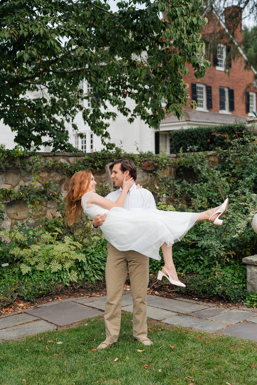 Couple spinning in a garden of colorful dahlias, creating an energetic and joyful moment captured with unique engagement shoot ideas at Stevens-Coolidge House & Gardens